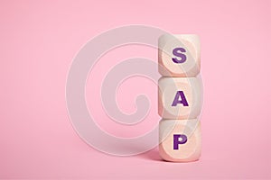 SAP, acronym on wooden cubes on Pink background