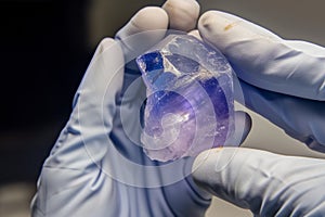 sapphire in rough form held by gloved hands