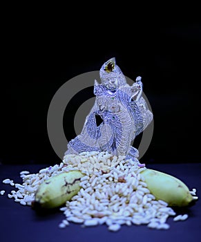 Saraswathi Pooja and Ayudha Pooja Celebrations - Silver idol Murugan with banana and pori on black background.