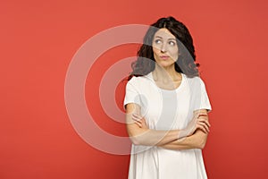 Sarcastic doubtful woman judgmental look with skeptical face aside to empty copy space over red wall