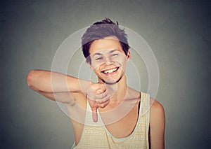 Sarcastic happy young man showing thumbs down hand gesture