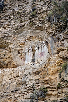 The sarcophagi of KarajÃ­a, Chachapoyas, Peru. These clay tombs have human forms and are set along the edge of a rock cliff.
