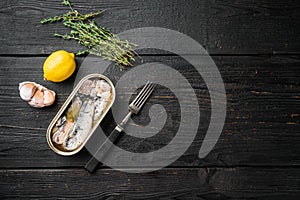 Sardines can preserve, on black wooden table background, top view flat lay, with copy space for text