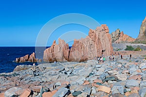 Sardinia Coastline: Typical Red Rocks and Cliffs and Tourists near Sea in Arbatax; Italy