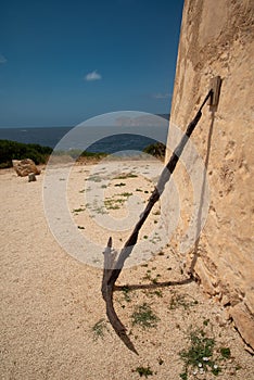 Sardinia, Italy. Old anchor against a wall, historic defensive tower