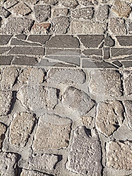 Sardinia. Traditional architecture. Urban road paved with rough ashlars and polished slabs of local volcanic stones. Detail