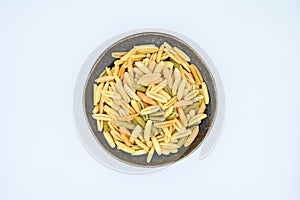 Sardinian gnocchetti pasta, also known as malloreddus or macarrones de punzu, in a dark grey bowl, isolated on a white background photo