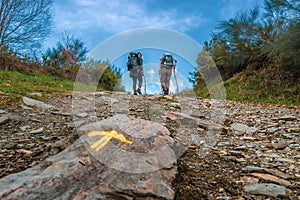 Sarria, Spain - Two Pilgrims Hiking up a Hill with the Yellow Arrow Way Mark outside Sarria along the Way of St James el Camino photo