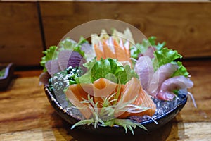 Sashimi salmon and seafood fish in black bowl decoration with vegetable on table.Japanese traditional food