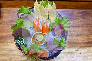 Sashimi salmon and seafood fish in black bowl decoration with vegetable, wasabi on table.