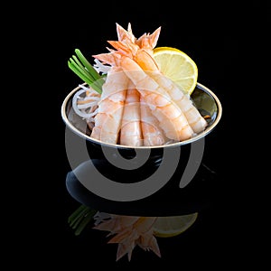 Sashimi with shrimp in a black plate. On a black background with