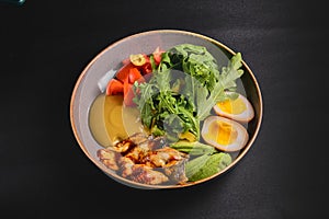 Sashimi Sushi with eel, boiled eggs, avocado, fresh tomatoes and arugula in a plate over black background.