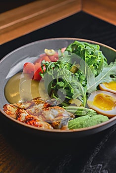 Sashimi Sushi with eel, boiled eggs, avocado, fresh tomatoes and arugula in a plate over black background.