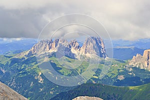 Sassolungo towers hidden in the clouds. Sharp edges, green grass, Dolomites.