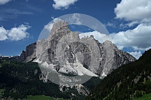 Sassongher above Corvara in the Dolomites, Epic Mountain in South Triol, SÃÂ¼dtirol with some clouds above and dark forest beneath photo