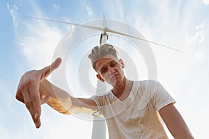 A sassy teenager on a blue sky background. Close-up of stylish hipster guy next to a windmill. Teenage years concept.