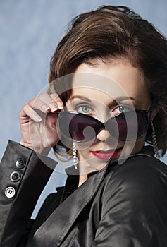 Sassy woman posing with sunglasses, red lipstick and a jacket