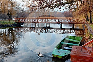Sasto lake with a boat and a duck in the front and a wooden bridge