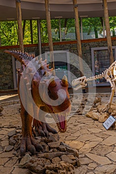 SATAPLIA, KUTAISI, GEORGIA: A statue of a moving dinosaur and a skeleton in the museum in the reserve in Sataplia.