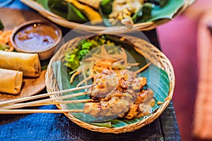 Satay or sate, skewered and grilled meat, served with peanut sauce, cucumber and ketupat. Traditional Malaysian and