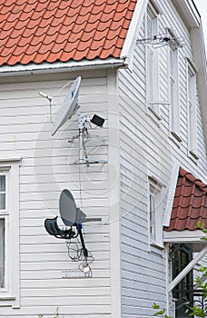 Satelite dishes and antenna on a white wooden house