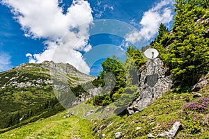 Satellite antenna mounted on a rock, around the green mountains. Beautiful summer mountain landscape - blue sky with white clouds