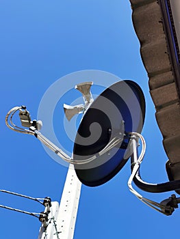 Satellite in the blue sky, on the roof of a house with the eletrical pole photo