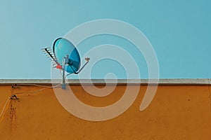 Satellite dish and antenna with antennas to receive digital TV and radio signals on top of brown building..