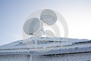 Satellite dish and antenna is covered by by frozen snow, ice