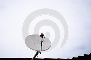 Satellite dish antenna isolated on house roof, sky background