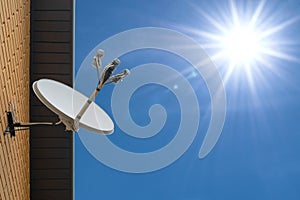 Satellite dish antenna mounted on the wall of a private house on blue sky background