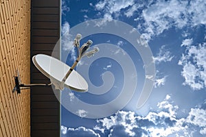 Satellite dish antenna mounted on the wall of a private house on blue sky background