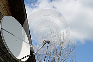 Satellite dish on a country house on a background of a blue sky with clouds.