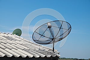 Satellite dish on the roof with blue sky.