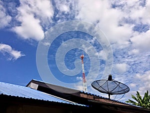 The satellite dish is on the roof with a telephone pole in the background