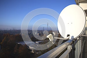 Satellite dish and TV antenna on the balcony of a appartment with a power station on the background