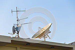 Satellite dish and TV antennas on the house roof with blue sky background