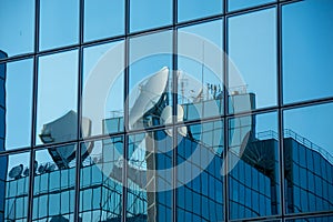 Satellite dishes reflected in the windows of a modern office building