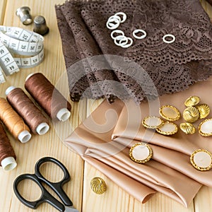 Satin fabric, lace and tailoring tools on wooden background