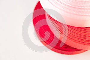 Satin ribbon rolls red and pink colors with copy space and selective focus on white background, horizontal. Silk tapes