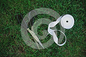 Satin white ribbon and scissors on grass