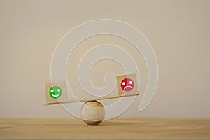 Satisfaction survey concept: Symbol icon smiley face and a sad face on wood block cube a balance scale in unalike. depicts the