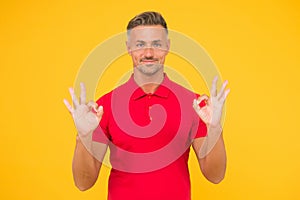 Satisfactory result. Happy man show double OK signs yellow background. Satisfied guy smile with satisfaction. Agreement
