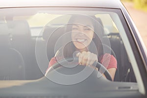 Satisfied attractive woman learns drive car, being in good mood as has positive resuls, drives by herself, keeps hands on wheel, h