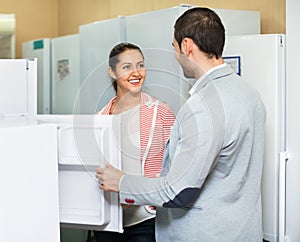 Satisfied beautiful couple looking at large fridges