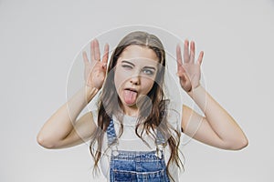 Satisfied beautiful young girl with long hair standing on a white background. Has an intriguing expression, looks with