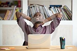 Satisfied African American leaning in chair happy with work res