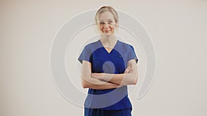 satisfied blonde Caucasian nurse with arms crossed and nodding medium shot isolated studio shot copy space medical