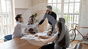 Satisfied boss handshake employee at group meeting thanking or welcoming