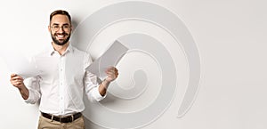 Satisfied boss smiling while holding good report, reading documents, standing over white background